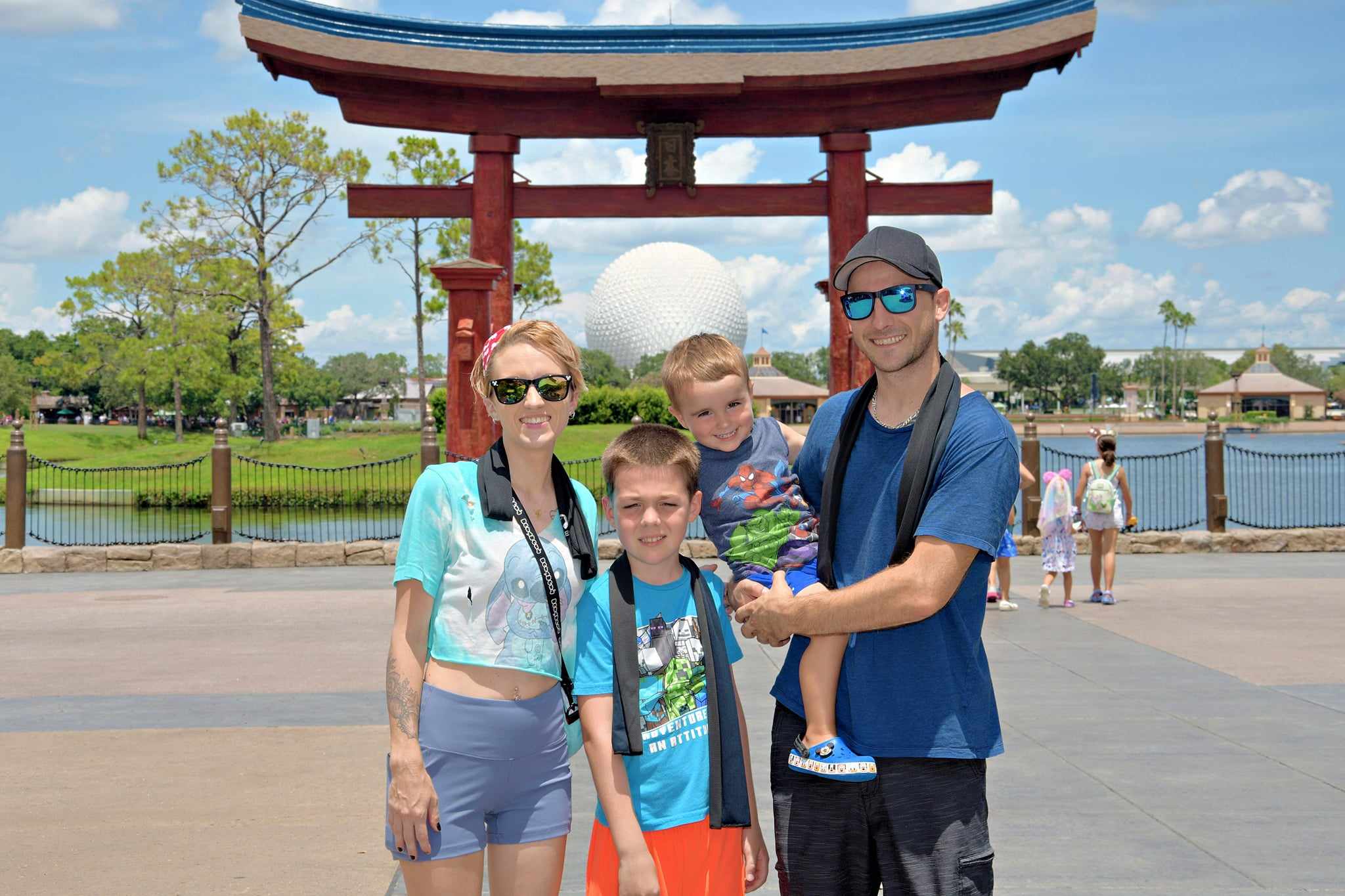 Family of four posing in front of a traditional Japanese archway with a park in the background.